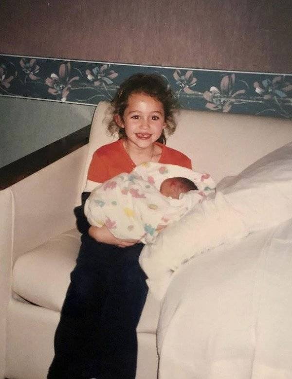 9. Майли Сайрус держит на руках своего брата Ноя Сайруса в 2000 году.