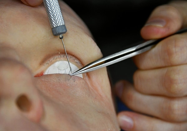 Сотрудник поправляет ресницы на лице робота-гуманоида, разработанного Promobot.