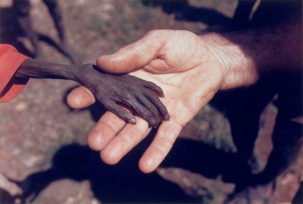 29. Bir misyoner, Uganda'nın Karamoja semtinde açlıktan ölmek üzere olan bir çocukla el ele tutuşuyor.