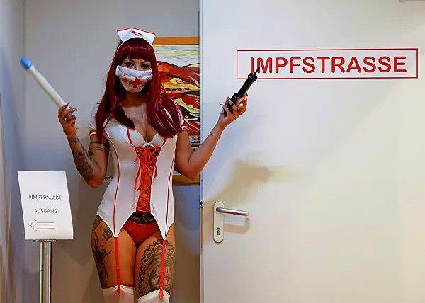 Viyana'daki aşı merkezinde hemşire kostümü giyen bir kadın, aşı olmak isteyenleri karşıladı.