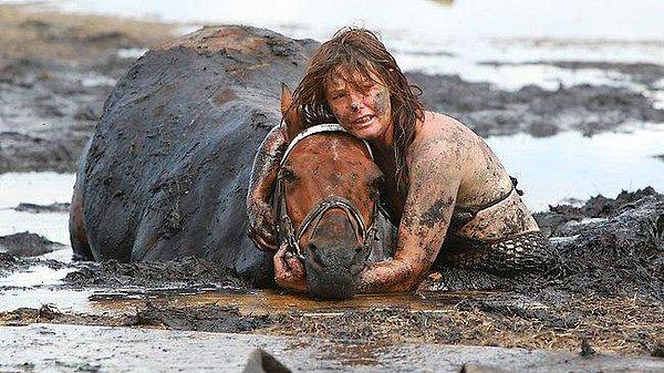 22. Çamura saplanan atının nefes alabilmesi için 3 saat boyunca yardım beklerken başını havada tutan kadın