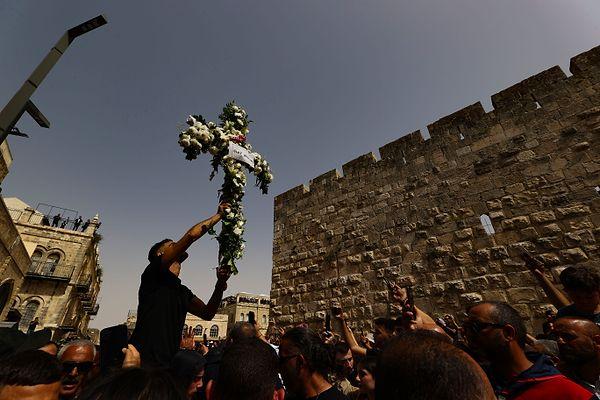Hristiyan Filistinli gazetecinin naaşı, çiçeklerle süslenmiş haç eşliğinde ve tekbir sesleriyle ilerledi.