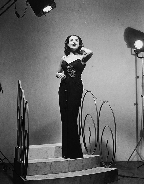 4. Lena Horne, yere kadar uzanan elbisesiyle bir sahne merdiveninde şarkı söylüyor.