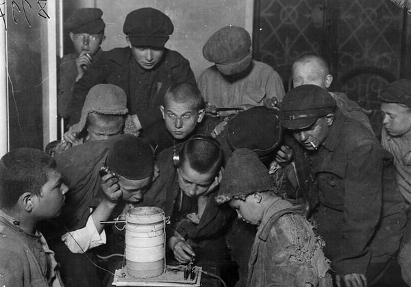 7. Беспризорники в общежитии у приемника слушают радио. Москва, 192