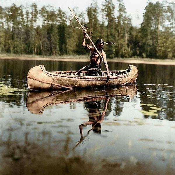 6. Ojibwe halkına ait bir yerli Amerikalı, Minnesota'da bir gölde zıpkınla balık tutuyor. (1908)