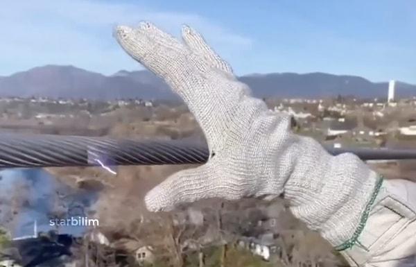 Bir kişi yüksek gerilim hattının elektomanyetik alanının yanı sıra, doğrudan dokunulduğunda neler olabileceğini gözlemlemek için özel eldivenlerle bir deneme yaptı.