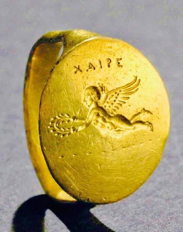 14. Uçan Eros'un tasvir edildiği altın yüzük. Çerçevede iki elinde bir çelenk tutan Eros'un sola doğru uçtuğu görülüyor. (M.Ö 330)