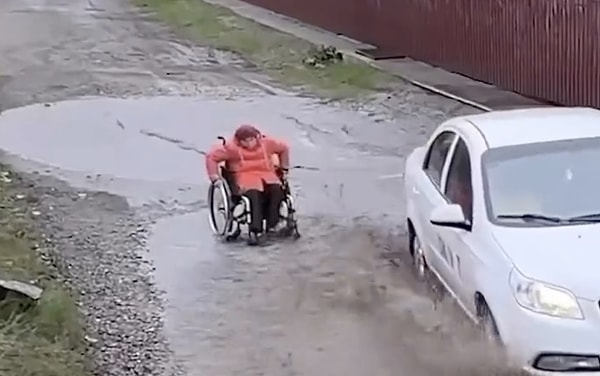 Engelli bir bireyin yağmurlu havada bir su birikintisinde takıldı.