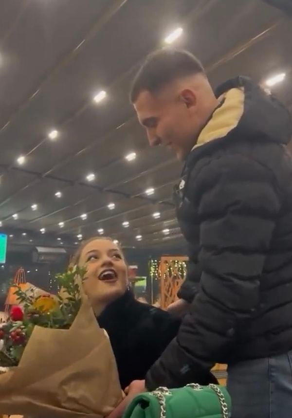 Genç adam elinde çiçeğiyle kız arkadaşının arkasından gelerek kadraja dahil oldu.
