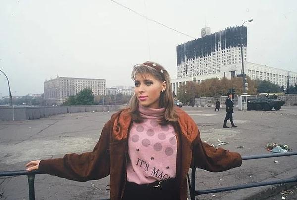 6. Anayasal krizin ardından arka planda yanmış Parlamento binası ve bir BTR askeri aracıyla poz veren bir Rus kadın. (Moskova, 1993)