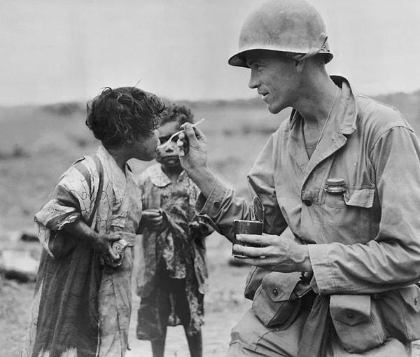 7. 1945'te Okinawa adasında erzağını iki Japon çocukla paylaşan Amerikalı bir asker.