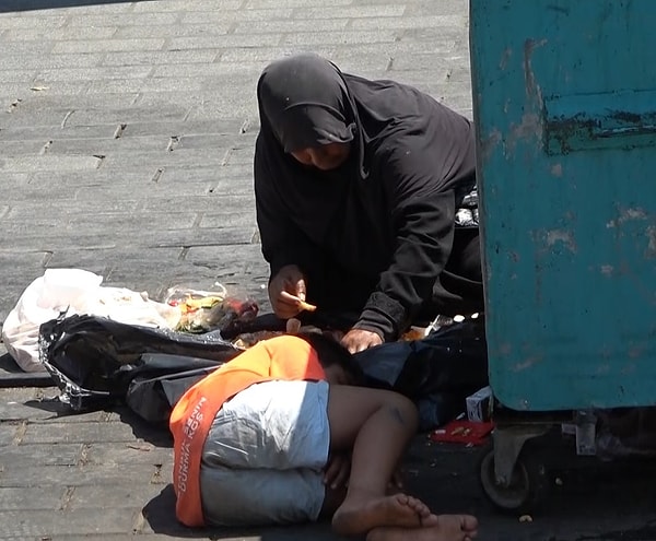 Dün öğle saatlerinde yaşanan olayda çöp konteynerinin yanına çocuğuyla birlikte oturan bir kadın dilencinin haline acıyan turistler, kadına para verdi.