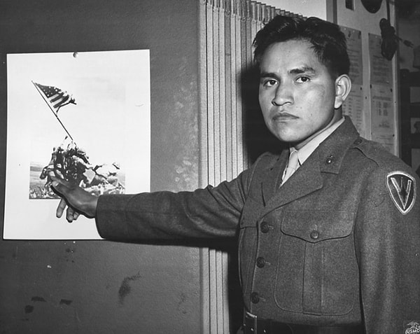 7. U.S. Marine Hayes pointing himself out in the famous "Raising the Flag on Iwo Jima" photograph.