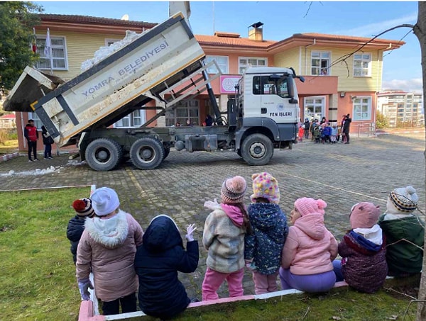 Okul bahçesine giren kamyonu alkışlarla karşılayan çocuklar, öğretmenleriyle birlikte kar topu oynayıp kardan adam yaparak keyifli anlar yaşadı.