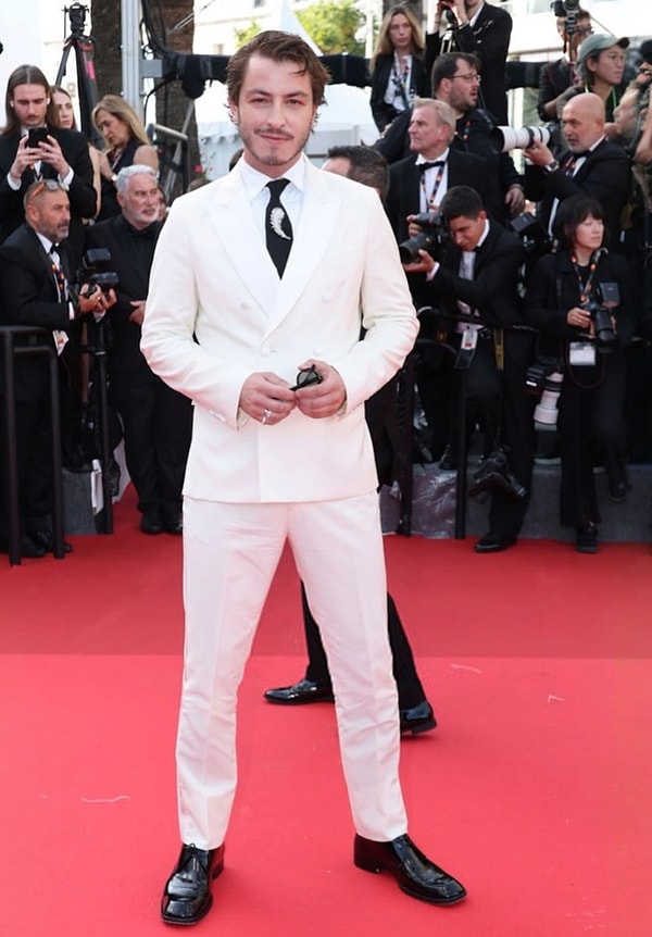 Boran Kuzum bu sefer Cannes kırmızı halısına yetişti! Beyaz takım elbisesi ve kravatındaki broş ile dikkat çeken oyuncu eleştirilerin hedefi olmaktan kaçamadı.