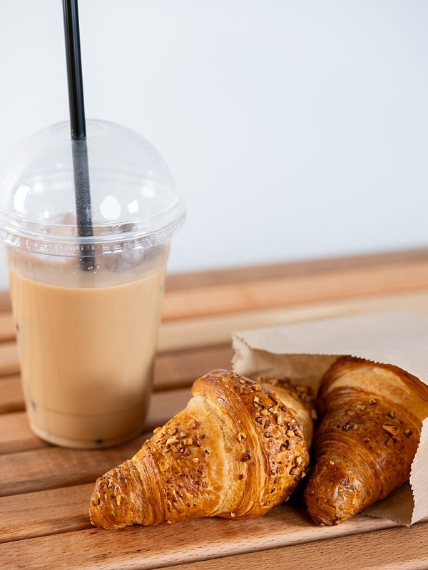 7. Iced Latte & Kruvasan İkilisi: Bir kahvecide, badem sütlü büyük boy Iced Latte ve taze pişmiş sade tereyağlı kruvasan.