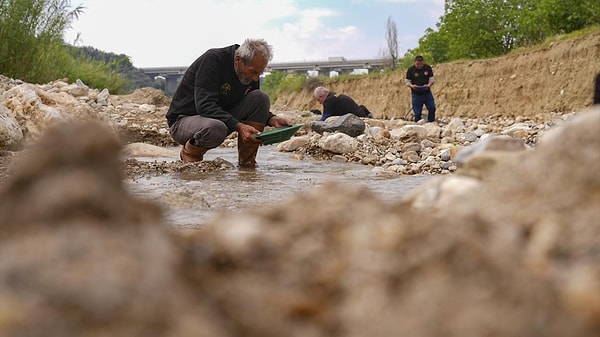 Dere yatağından alınan kum, su yardımıyla eleniyor.